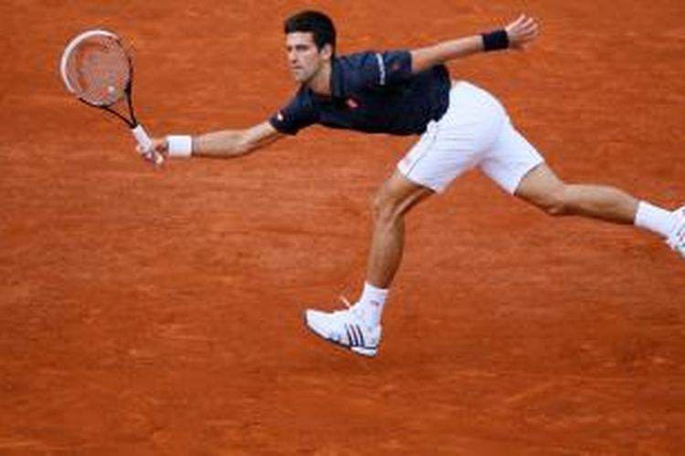 Petenis Serbia Novak Djokovic memukul bola ke arah petenis Kanada, Milos Raonic, saat keduanya bertemu di perempat final French Open di Paris, Selasa (3/6/2014).