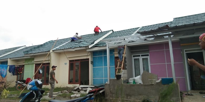 Warga tengah memperbaiki atap rumah yang tersapu angin puting beliung di Perum Pelangi Regency, Desa Pangulah Selatan, Kecamatan Kotabaru, Kabupaten Karawang, Senin (1/2/2021).