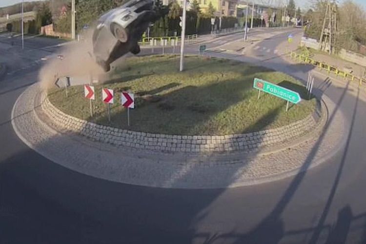 Tangkapan layar dari video yang menunjukkan detik-detik mobil terbang setelah menghantam bundaran jalan raya di Polandia.