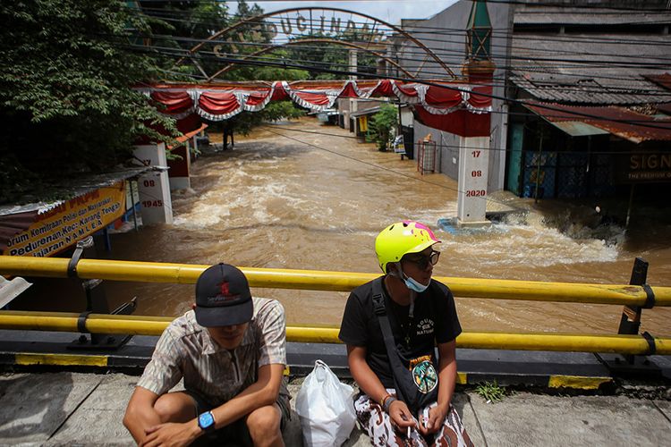 Warga duduk dengan latar belakang air yang memasuki perumahan Ciledug Indah, Kota Tangerang, Banten, Sabtu (20/2/2021). Banjir setinggi hingga 2 meter tersebut diakibatkan oleh luapan Kali Angke.