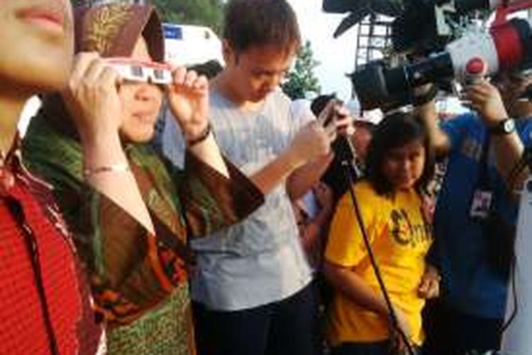 Wali Kota Surabaya Tri Rismaharini mengenakan kacamata khusus untuk melihat gerhana matahari dari Pantai Kenjeran, Surabaya, Jawa Timur, Rabu (9/3/2016).