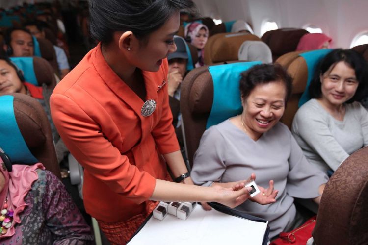 Pramugari Garuda Indonesia membagikan cokelat di tengah Kartini Flight rute Jakarta-Padang, Jumat (21/4/2017).