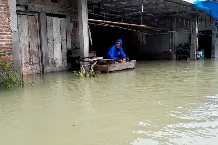 Salah seorang warga di Desa Cangkring, Kecamatan Karanganyar, bertahan di dipan saat banjir datang, Minggu (17/3/2024). 