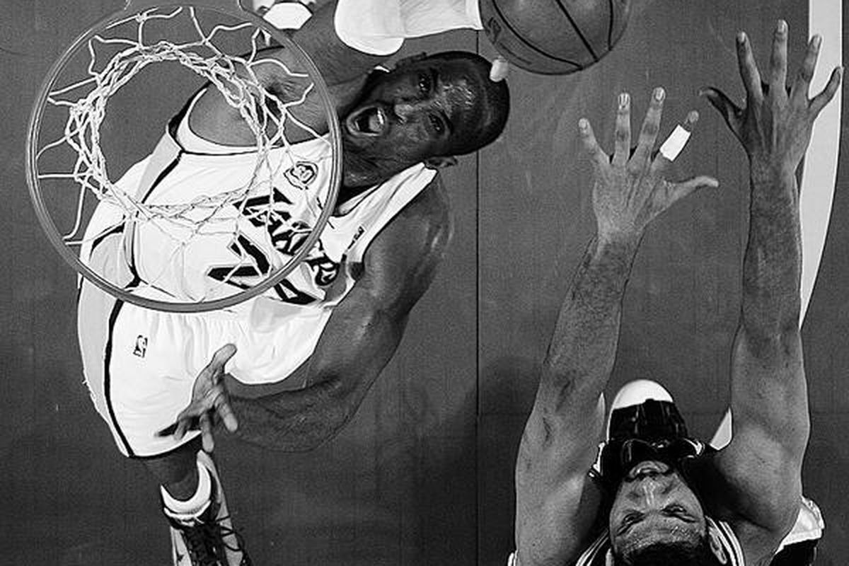 Pemain andalan Los Angeles Lakers, Kobe Bryant, mencetak angka dari bawah ring tanpa bisa diblok oleh pemain San Antonio Spurs, Tim Duncan, pada pertandingan NBA, Minggu (13/4) di Los Angeles, AS.  