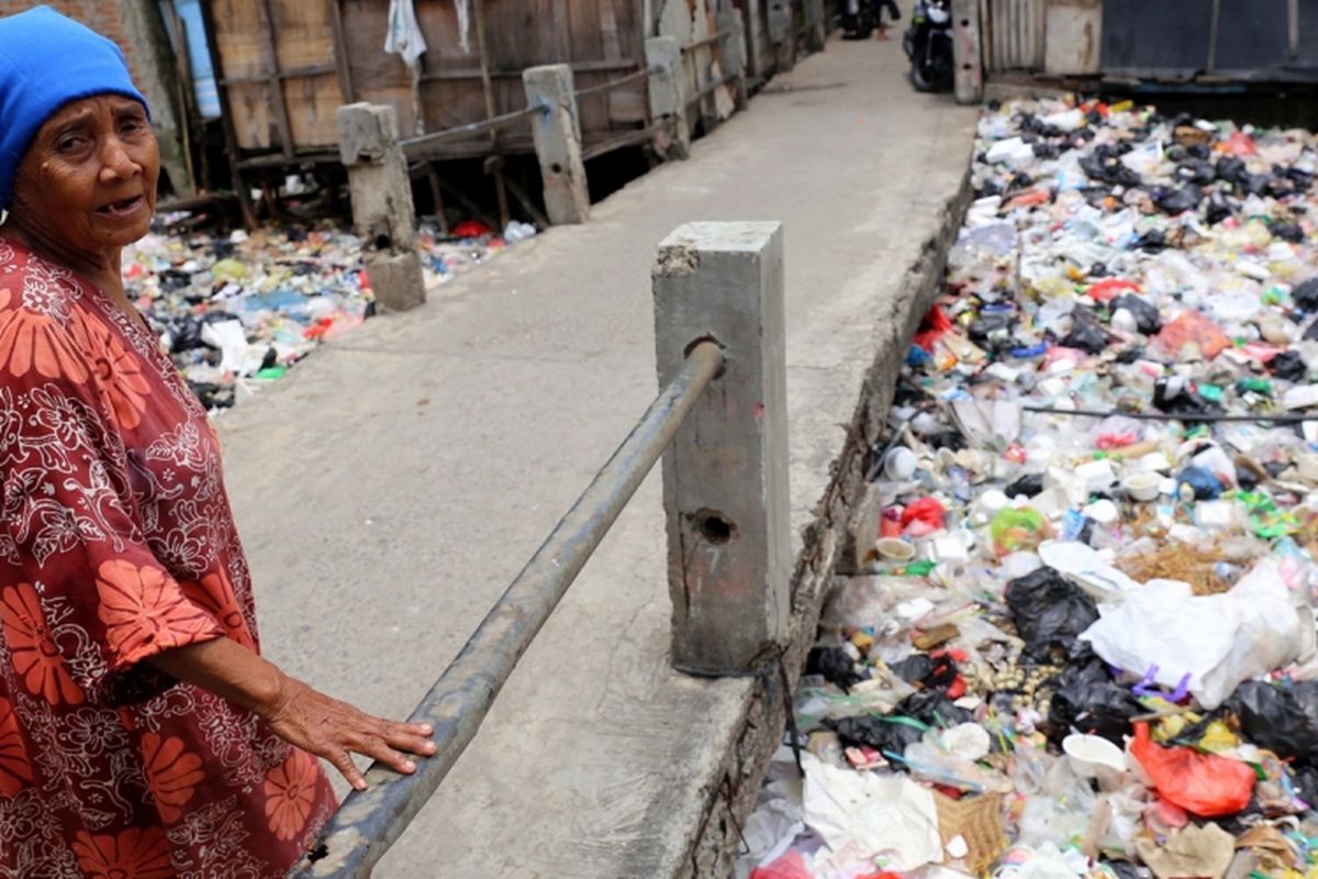 Warga melintas di Kali Gendong, Waduk Pluit, Penjaringan, Jakarta Utara, Selasa (14/3/2017). Kurangnya kesadaran masyarakat membuang sampah sembarangan mengakibatkan sampah plastik dari rumah tangga nyaris menyerupai daratan tersebut menumpuk di sepanjang Kali Gendong.