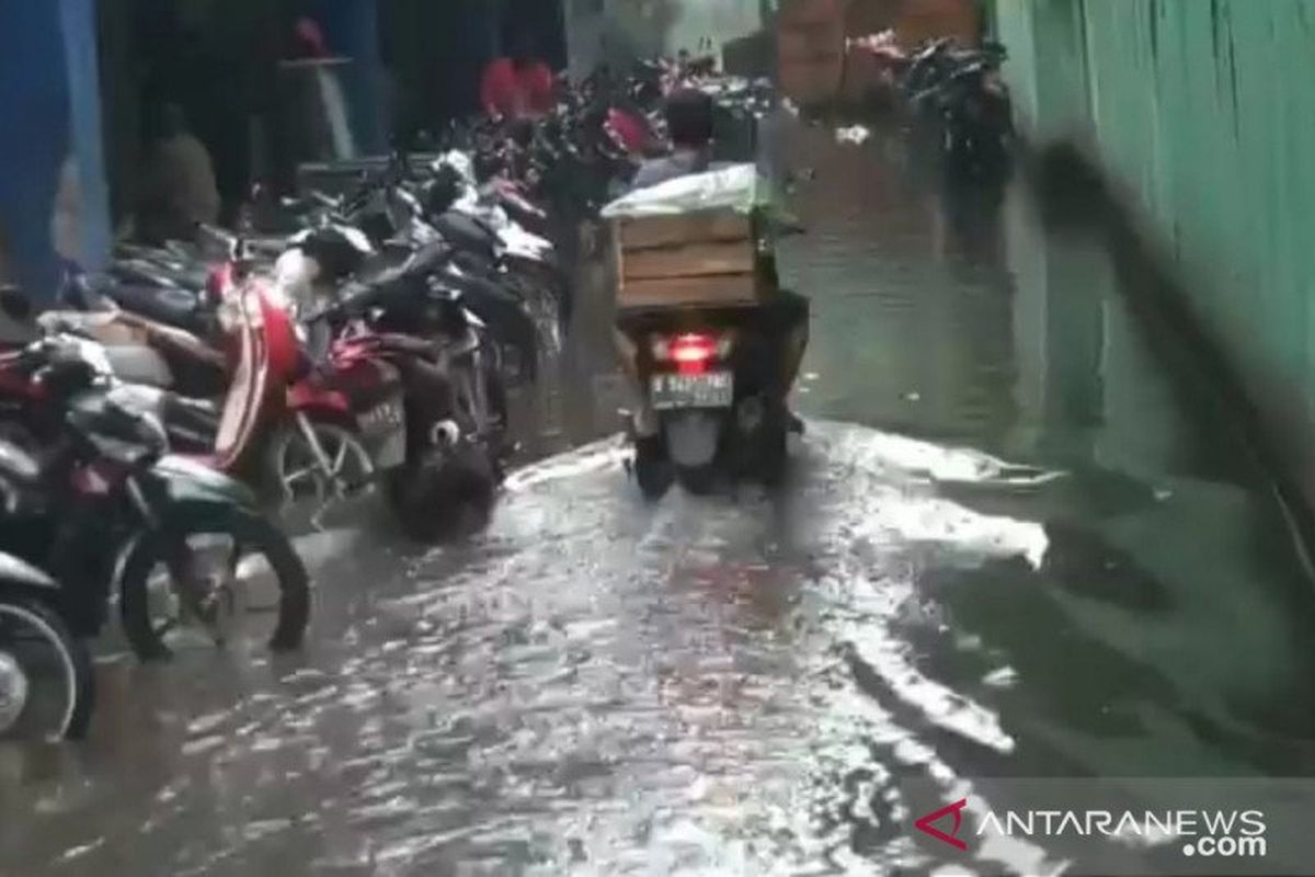 Pengendara melintas di area parkiran kendaraan Pasar Cibubur, Jakarta Timur, saat terjadi genangan akibat mesin pompa rusak, Sabtu (13/2/2021).