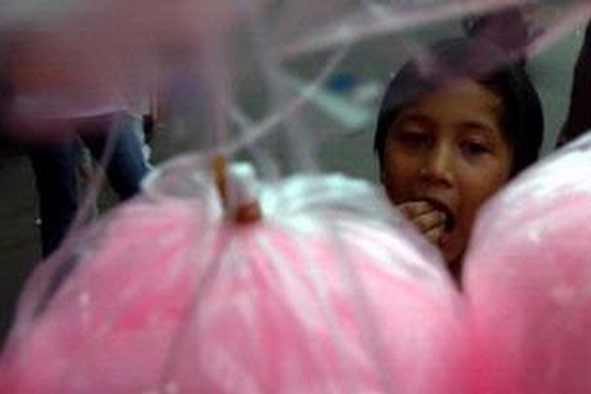 Seorang anak mengamati kembang gula yang dijual.