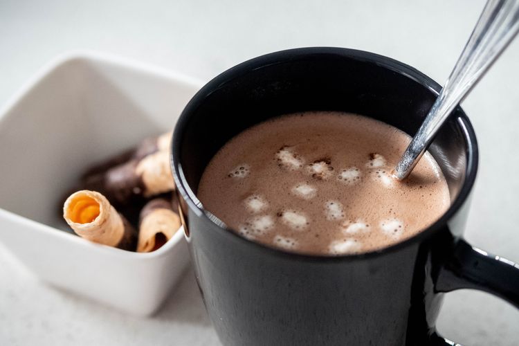 Ilustrasi susu cokelat hangat dan camilan. 