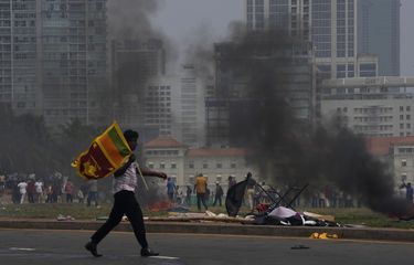 Seorang pendukung Pemerintah Sri Lanka membawa bendera negara setelah bentrok dengan massa anti-pemerintah di luar kantor presiden di Colombo, Sri Lanka, Senin (9/5/2022).