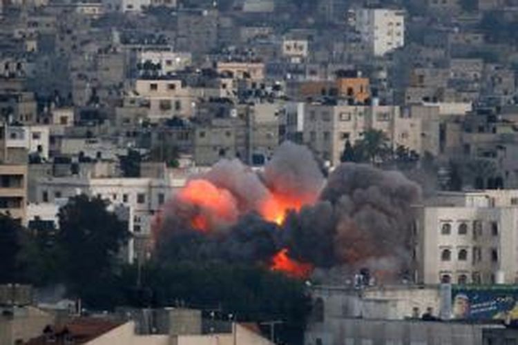 Api menyala dari sebuah bangunan di kawasan padat penduduk di Gaza City, Jalur Gaza, Palestina, Rabu (9/7/2014), setelah menjadi sasaran serangan udara Israel. 