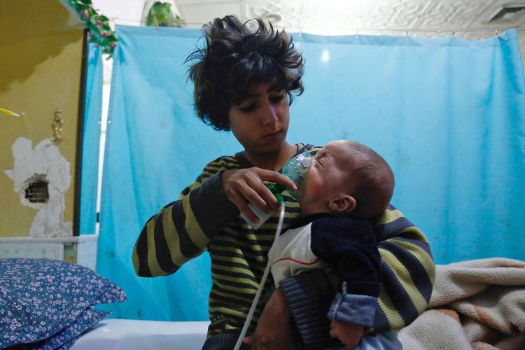 Seorang bocah Suriah memberikan masker oksigen di wajah bayi menyusul laporan serangan racun gas di Douma, timur Ghouta, pada 22 Januari 2018. Pada 2019 ini, Amerika Serikat menyatakan rezim Presiden Suriah Bashar al-Assad kembali menggunakan senjata kimia ke warga sipil untuk menghantam benteng terakhir pemberontak.