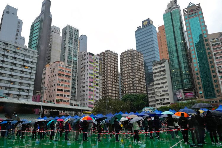 Meski diguyur hujan, warga mengantre untuk menjalani tes virus corona di pusat pengujian sementara di Hong Kong, Senin, 21 Februari 2022. 