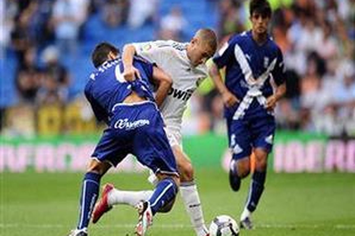 Striker Real Madrid, Karim Benzema (tengah), berusaha melewati penjagaan Pablo Sicilia dari Tenerife dalam duel lanjutan Liga Divisi Primera Spanyol, Sabtu (26/9).