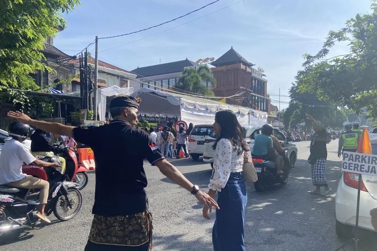 Pecalang di Desa Pakraman membantu anggota jemaat menyebrangi jalan untuk menuju ke GPIB Maranatha guna menghadiri perayaan Natal 2023 di Kota Denpasar, Provinsi Bali, Senin (25/12/2023). (ANTARA/Ni Putu Putri Muliantari)