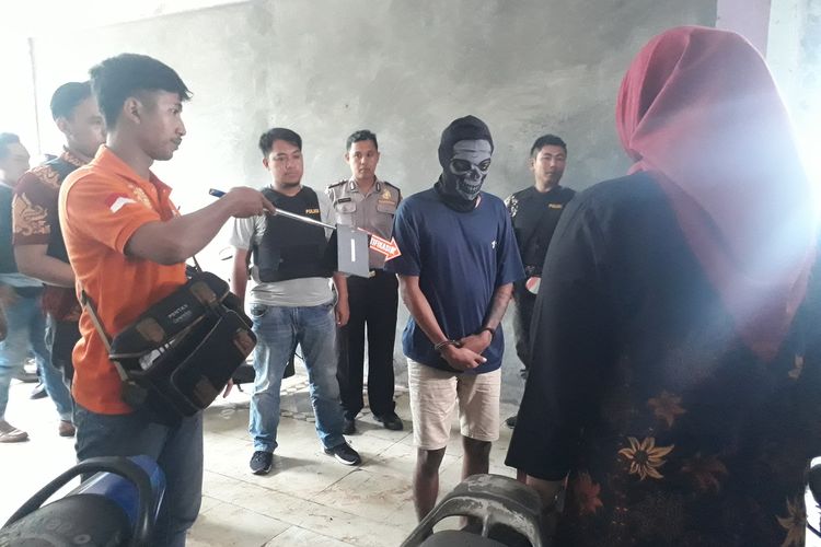 JE (bertopen), pelaku pembunuhan driver ojek online bernama Rieke Andrianti memperagakan adegan saat hendak membunuh korbannya di Rumah Susun Griya Tipar Cakung, Jakarta Timur, Jumat (10/1/2020).