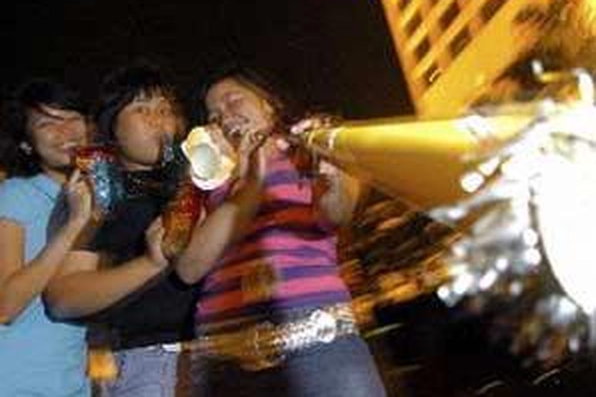 Tiga perempuan muda meniup terompet menjelang detik-detik pergantian tahun di seputaran Bundaran Hotel Indonesia, Jakarta.