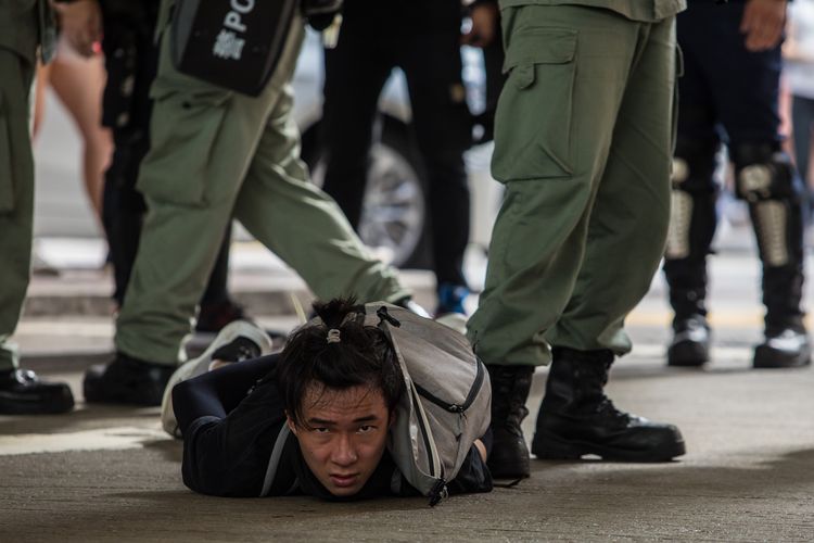 Polisi anti huru-hara Hong Kong ketika menahan seorang pria, di tengah upaya mereka membubarkan demonstrasi menentang penerapan UU Keamanan Nasional pada 1 Juli 2020, atau dalam peringatan 23 tahun penyerahan Hong Kong dari Inggris kepada China.