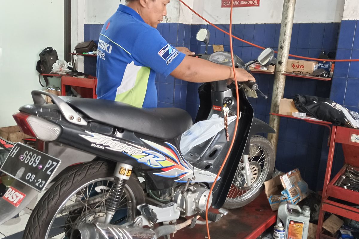 Mekanik bengkel suzuki sedang melakukan perawatan sepeda motor Suzuki Shogun. 