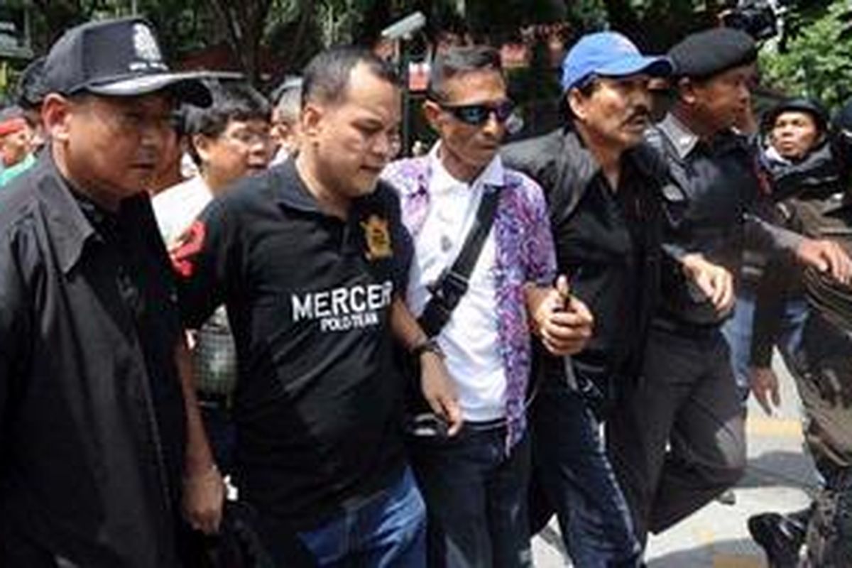 Pemimpin anti-pemerintah kelompok Kaus Merah, Nattawut Saikuar (kedua kiri) dan Wiphuthalang (topi biru) menyerahkan diri kepada polisi Thailand dalam penyerangan militer ke kamp pemrotes di kota Bangkok, Rabu (19/5/2010).