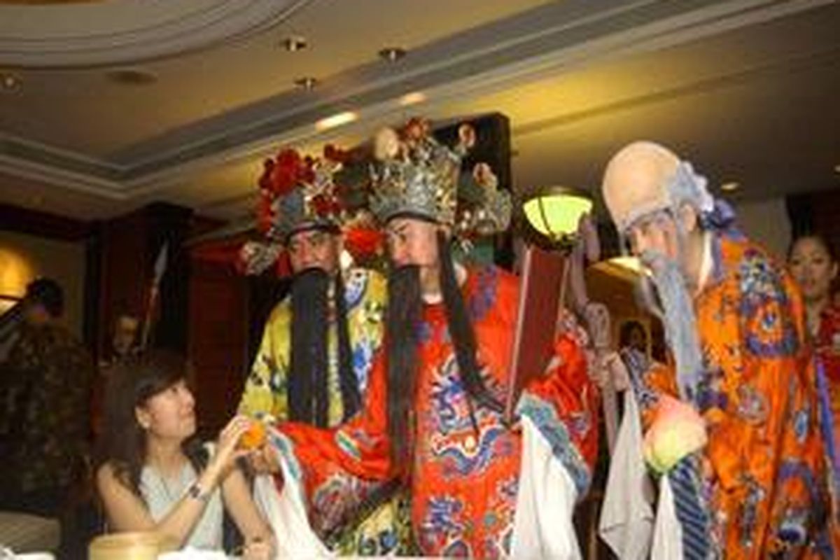 IMLEK - Tiga dewa Fu Lu Shou sedang memberikan buah jeruk kepada pengunjung Restoran Tang Palace Hotel JW Marriott Surabaya. Buah jeruk merupakan buah khas pada perayaan Imlek, dapat diartikan sebagai rezeki. 