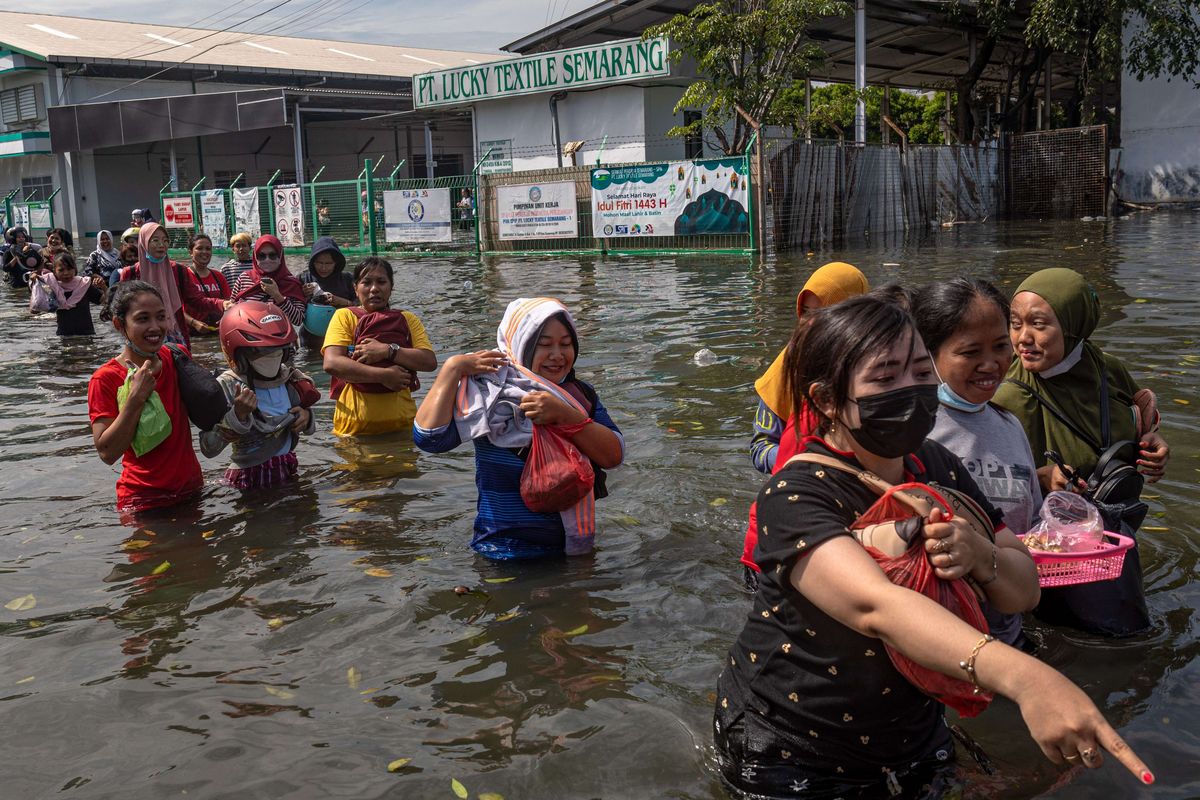 Sejumlah karyawan kawasan industri pelabuhan berjalan menerobos banjir limpasan air laut ke daratan atau rob seusai membersihkan pabrik mereka di kawasan industri Pelabuhan Tanjung Emas Semarang, Jawa Tengah, Jumat (27/5/2022). Karyawan sejumlah pabrik setempat mulai membersihkan sisa-sisa banjir rob di dalam pabrik yang berangsur surut, meskipun air rob masih merendam sejumlah titik akses keluar - masuk kawasan industri pelabuhan dengan ketinggian bervariasi hingga sekitar 70 sentimeter.