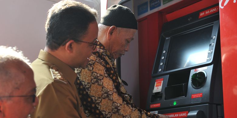 Gubernur DKI Jakarta Anies Baswedan sedang melihat lansia menggunakan Kartu Lansia Jakarta (KLJ).
