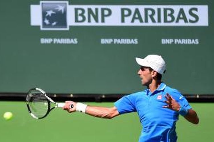 Petenis Serbia, Novak Djokovic, memukul bola ke arah petenis Inggris, Andy Murray, pada laga semifinal BNP Paribas Terbuka di Indian Wells, Sabtu (21/3/2015). Djokovic menang 6-2, 6-3.