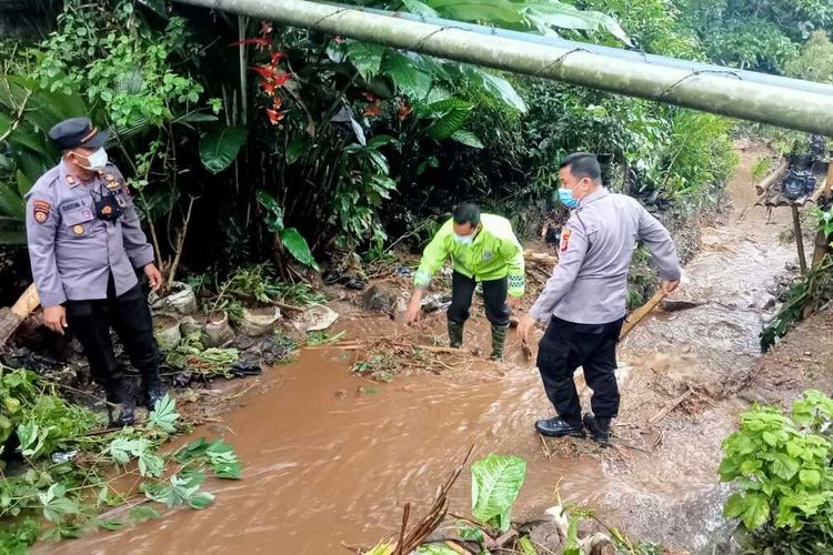 Anggota kepolisian ikut membersihkan material sisa banjir yang melanda Jalinbar Sumatera di Tanggamus.