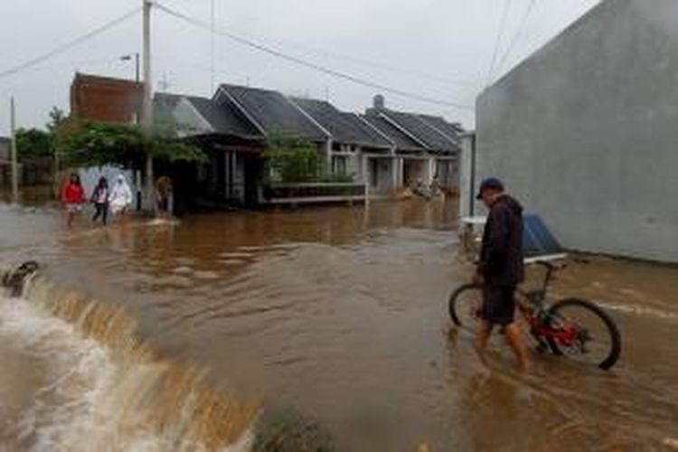 Warga melintas di Perumahan Cimanggis Country Residence, Kelurahan Tugu, Cimanggis, Depok, Senin (13/1/2014). Banjir disebabkan tanggul Kali Laya jebol akibat tak mampu menampung debit air yang meningkat drastis akibat hujan yang terus-menerus. KOMPAS IMAGES/KRISTIANTO PURNOMO