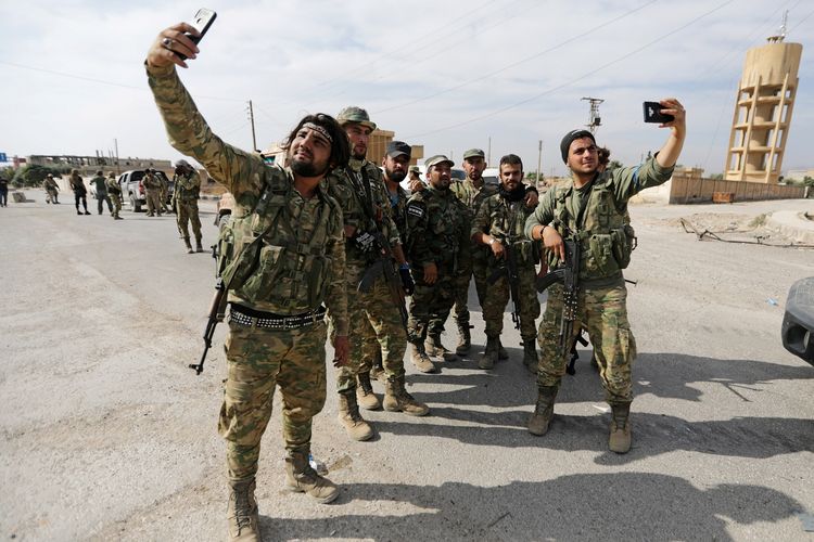 Tentara pemberontak Suriah yang mendapat dukungan Turki mengambil gambar dengan ponsel di kota perbatasan Tel Abyad, Suriah, Senin (14/10/2019).