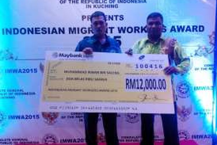 Muhammad Irwan (kiri) dan manager Sarawak Oil Palm Berhad, Pennir Selwam (kanan) berfoto bersama usai menerima penghargaan dalam acara anugerah Indonesia Migrant Workers Award di Kuching, Sarawak, Malaysia (10/4/2016)