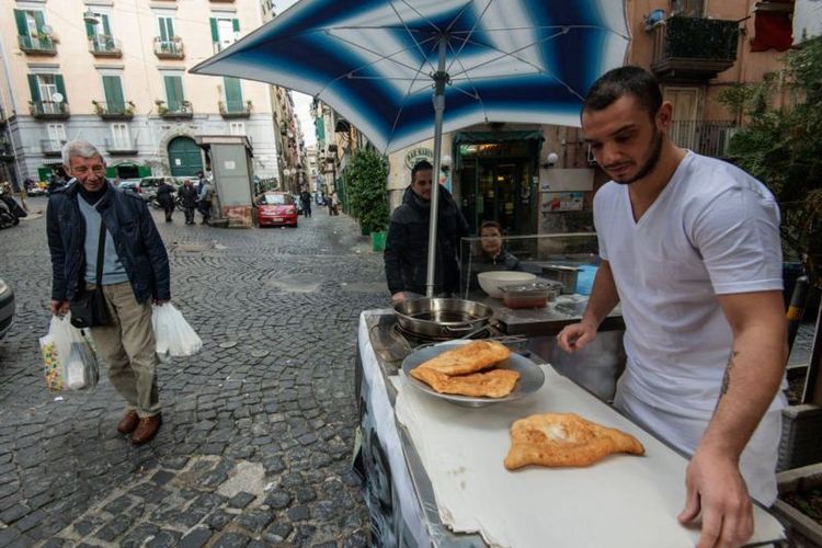 Seorang pedagang kaki lima di Napoli menjual pizza goreng.