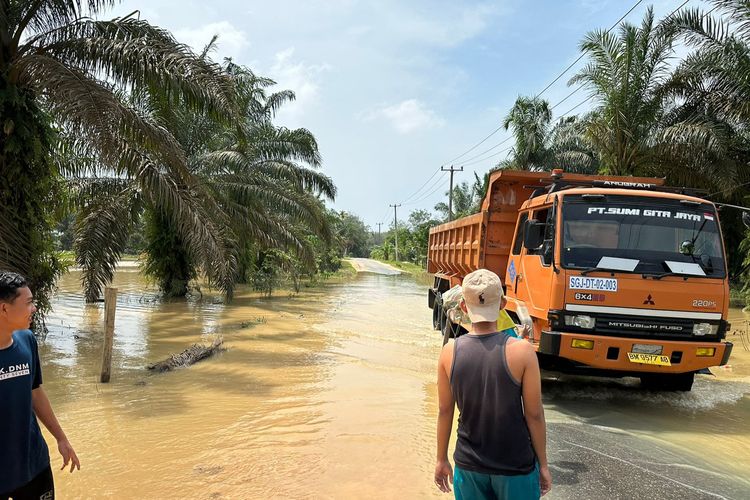 Sebuah mobil melintasi jalan yang terendam banjir di Desa Sungai Lipai, Kecamatan Gunung Sahilan, Kabupaten Kampar, Riau, Jumat (23/2/2024).