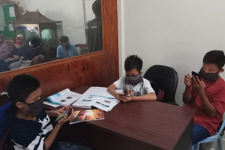 Beberapa siswa SMPN 4 Bengkalis, Riau, memanfaatkan akses wifi di aula Desa Kelapapati saat belajar daring bersama guru mereka. Dukungan dari pihak desa yang membuka akses wifi, membantu siswa yang kesulitan mengakses internet bisa belajar secara daring.