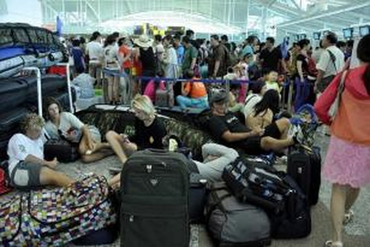 Penumpang internasional dengan barang-barang mereka berkerumun di depan counter check- in di Bandara Ngurah Rai di Denpasar, 11 Juli 2015. Para wisatawan terdampar beberapa hari di Bali ketika abu vulkanik letusan Gunung raung memaksa penutupan bandara.