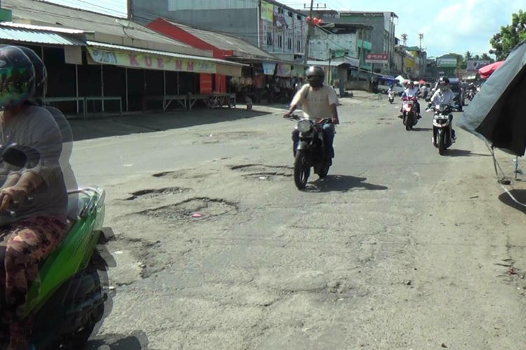 Warga melintas di Jalan Pasar Pagi Pangkal Pinang yang dipenuhi lubang.