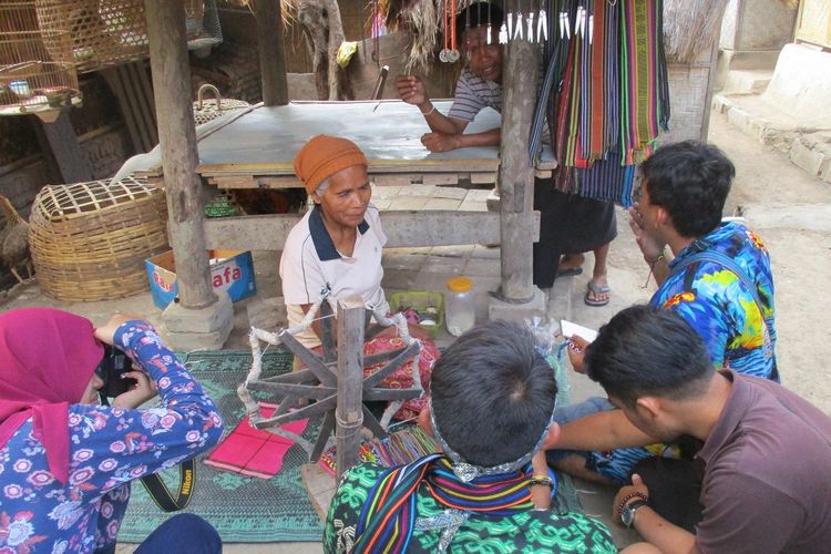 warga penjual kain tenun sedang dikelilingi pembeli