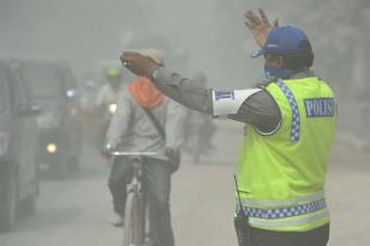 Diselimuti Abu Vulkanik -  Petugas kepolisian meminta para pengendara untuk menyelakan lampu akibat pekatnya abu vulkanik letusan Gunung Kelud Jawa Timur di Jalan MT Haryono, Kutoarjo, Kabupaten Purworejo, Jawa Tengah, Sabtu (15/2). 
Kompas/Wawan H Prabowo
