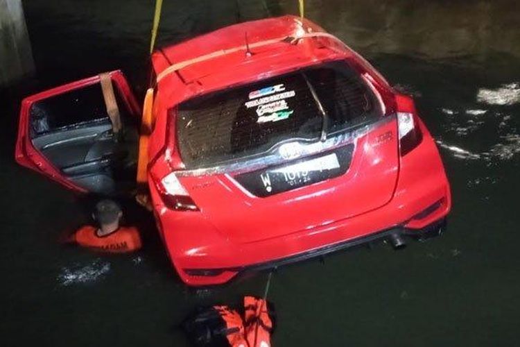 Anggota Tim Rescue PMK Surabaya menggunakan truk crane mengevakuasi mobil Honda Jazz bernopol L-1015-PB yang tercebur di sungai tengah Jalan Raya Prapen No. 266, Panjang Jiwo, Tenggilis Mejoyo, Kota Surabaya, Jumat (1/4/2022) dini hari. 