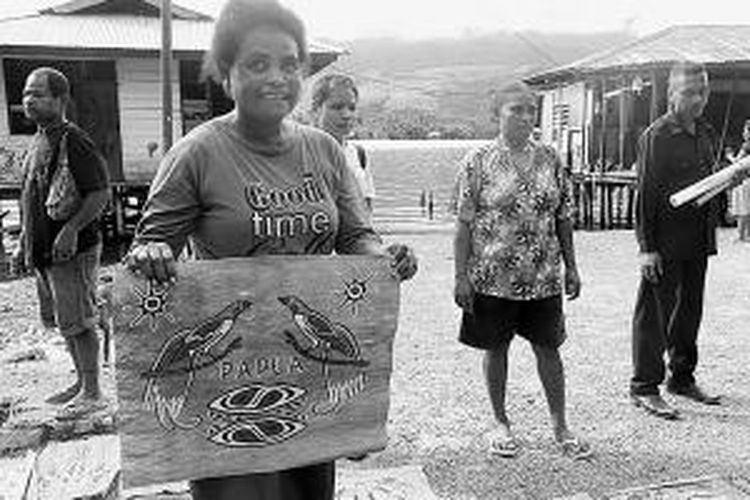 Warga Pulau Asei, Jayapura, Papua, menunjukkan karya lukisan mereka di atas kulit kayu.