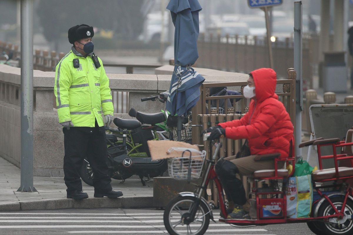 Seorang polsi memperhatikan jalan dengan pengguna melintas di hadapannya di Beijing, China, pada 21 Februari 2020 di tengah merebaknya virus corona.