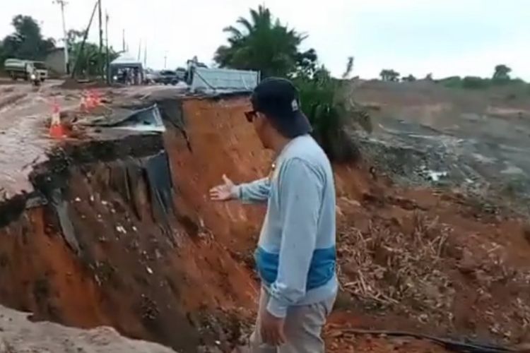 Seorang warga memperlihatkan kondisi Jalan Nasional di kilometer 171, Kecamatan Satui, Tanah Bumbu, Kalsel yang kembali longsor untuk ketiga kalinya pada, Minggu (16/10/2022). 