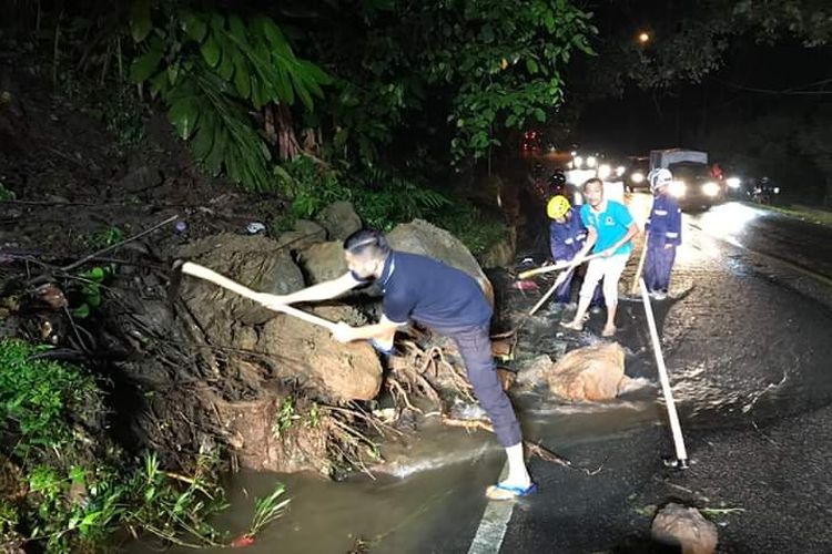 Petugas membersihkan material longsor di jalan nasional Padang-Padang Panjang, Jumat (14/6/2019) malam.