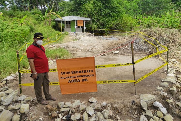 Sumantri, Sekretaris Desa Cipanas, menunjukan lokasi semburan lumpur di Desa Cipanas, Kecamatan Dukupuntang, Kabupaten Cirebon, Jawa Barat, yang sudah dipasang garis Satpol PP, Minggu (6/6/2021)