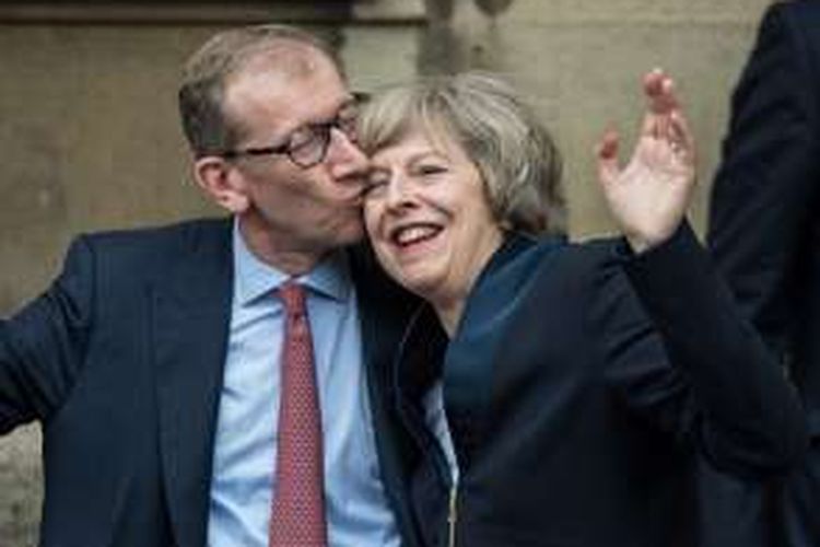 Pemimpin Partai Konservatif Theresa May dicum suaminya Philip John May, setelah memberikan keterangan kepada para jurnalis di pintu masuk Istana Westminster, London.