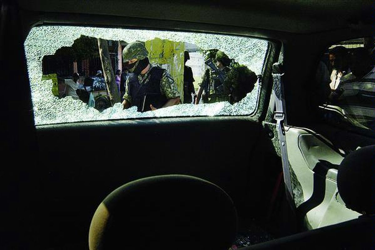 Sejumlah tentara terlihat di celah kaca mobil yang bolong saat melakukan inspeksi atas tindakan kriminal setelah kejadian tembak-menembak dan kejar-mengejar mobil di Acapulco, Meksiko, Sabtu (23/10). Setidaknya empat orang tewas di tempat ini.