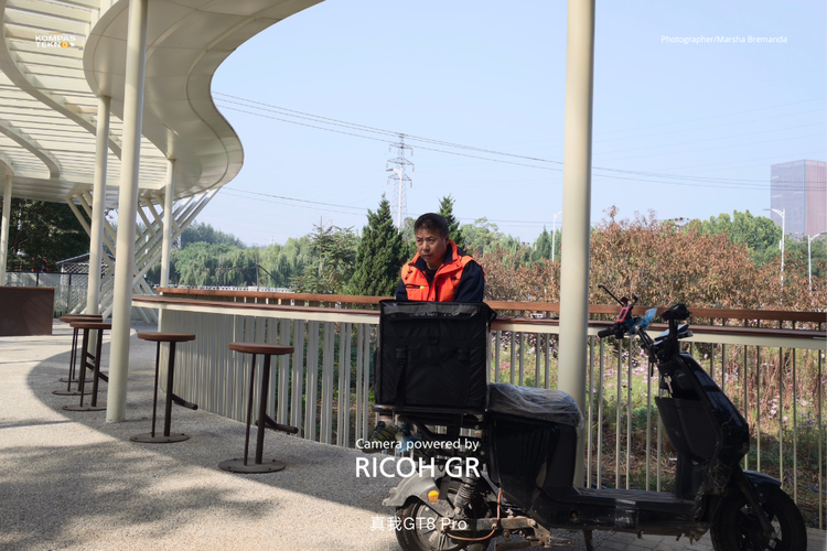 Hasil foto dengan tone Negative Film dari kamera Realme GT 8 Pro x Ricoh menampilkan nuansa warna yang lembut dan sedikit pudar dari potret seorang lelaki yang tengah duduk merenung. 