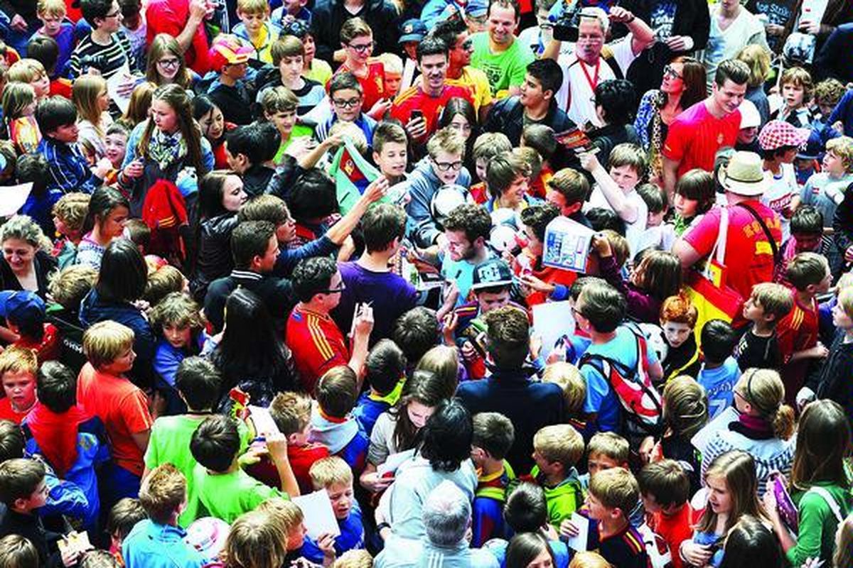   Para penggemar mengerubuti pesepak bola asal Spanyol, Juan Mata. Penggemar diundang masuk ke lapangan seusai sesi latihan, Senin (28/5), di Schruns, Austria.
