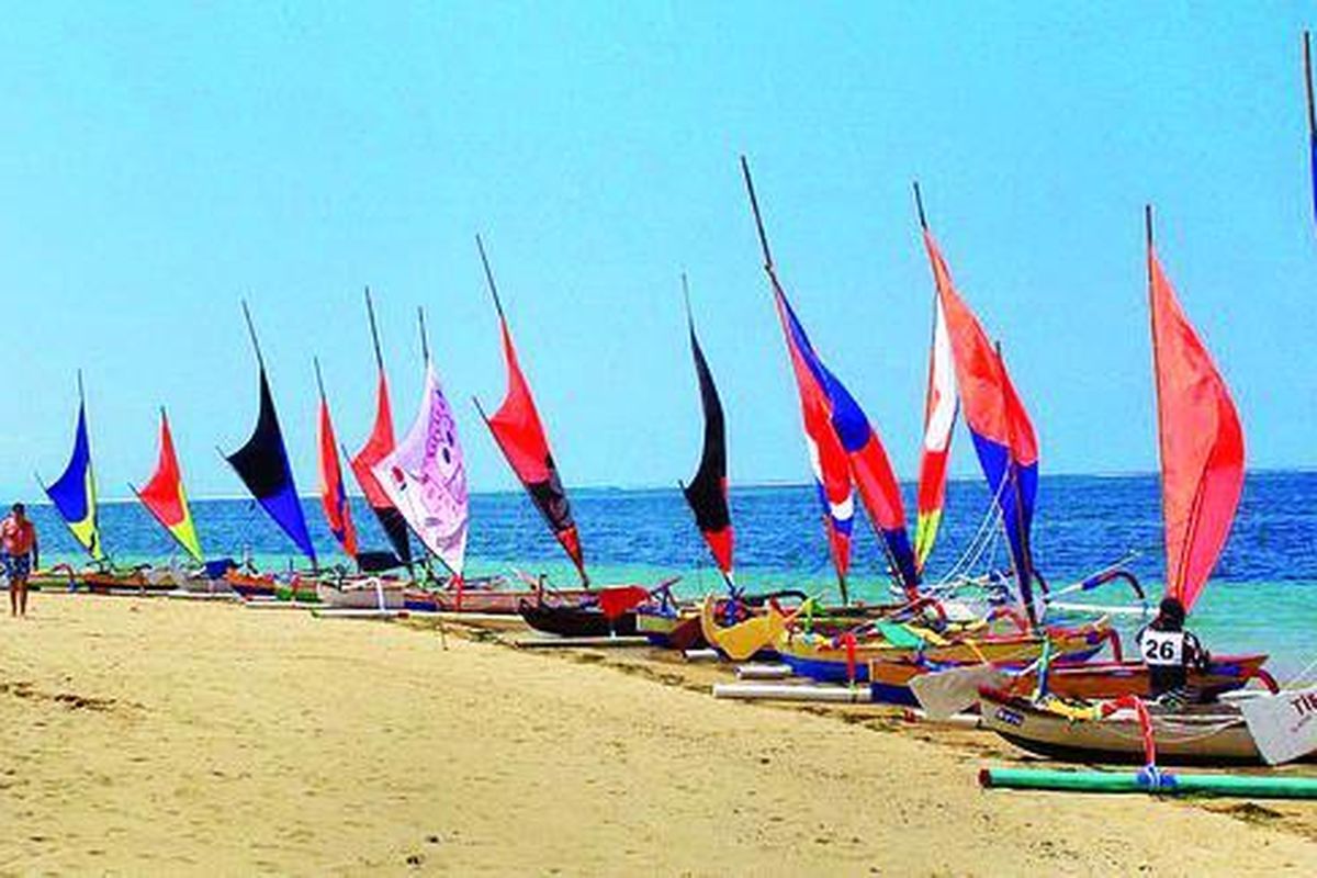 Sejumlah wisatawan mancanegara berjalan melewati jajaran perahu jukung di Pantai Mertasari, Jumat (6/8). Pawai perahu jukung merupakan salah satu materi dalam Sanur Village Festival kelima tahun ini.