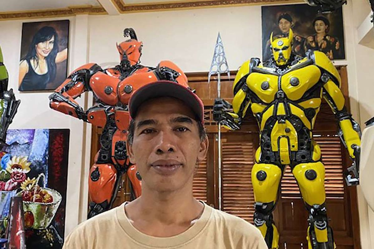 Eri Sudarmono di depan replika robot buatannya di Er Studio Art, Padukuhan Kauman, Kalurahan Gilangharjo, Kapanewon Pandak, Kabupaten Bantul, DI Yogyakarta, Kamis (14/11/2021). Sempat terpuruk dihantam pandemi, Eri Sudarmono yang sebelumnya seorang pelukis kini 'menyulap' motor tua menjadi replika robot yang bernilai ekonomi dan telah menembus pasar internasional.